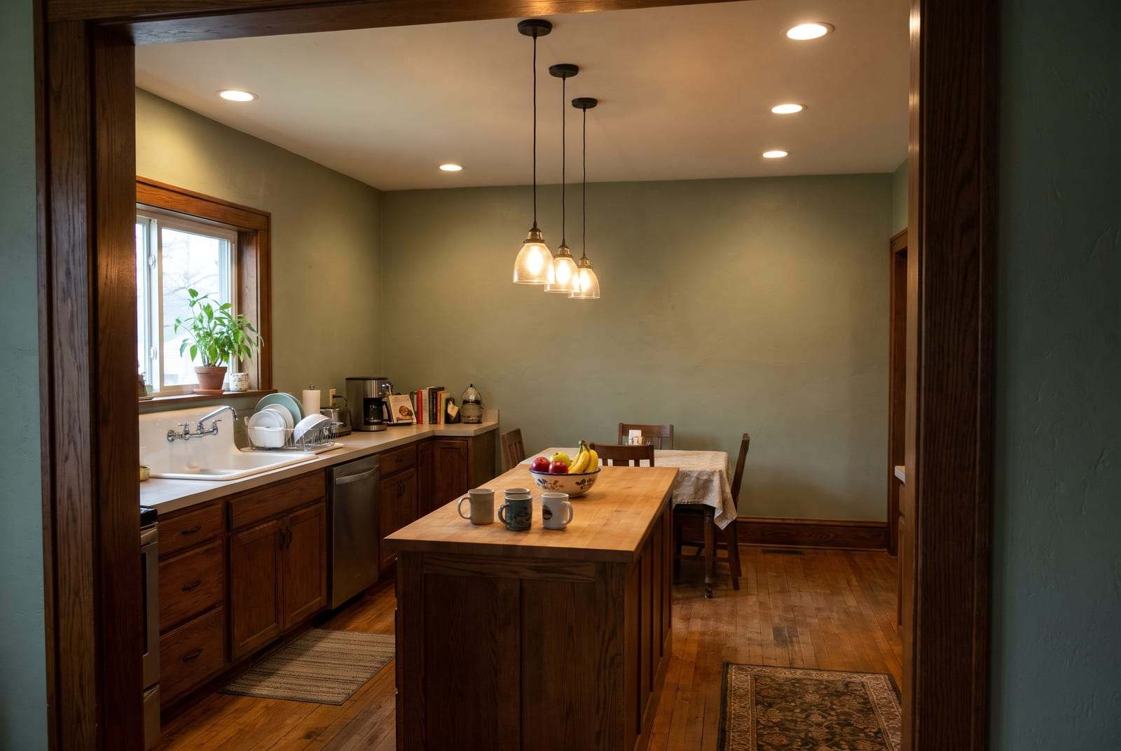 Kitchen with recessed ceiling lights and three glass pendants over a butcher-block island