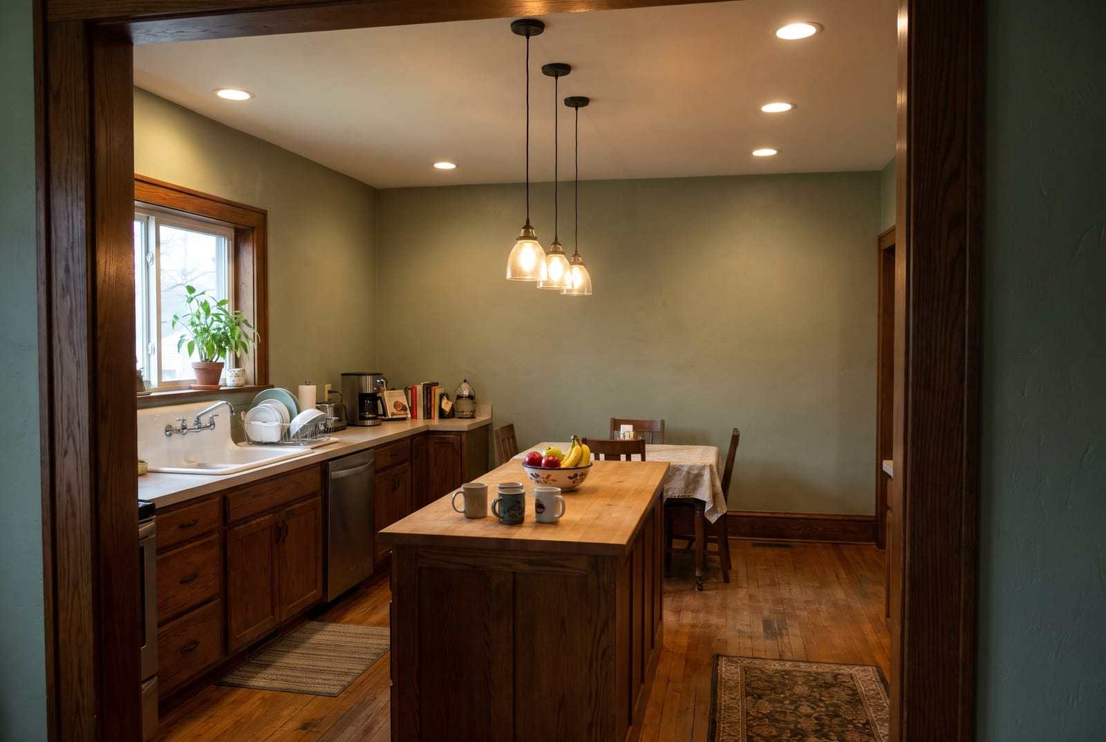 Kitchen with recessed ceiling lights and three glass pendants over a butcher-block island
